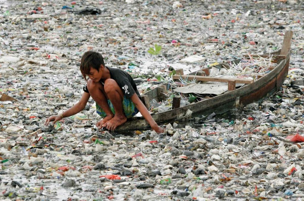 Ребёнок среди плавающего пластикового мусора
